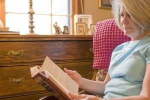 Old woman reading in her home living independently with her TGA mobility scooters